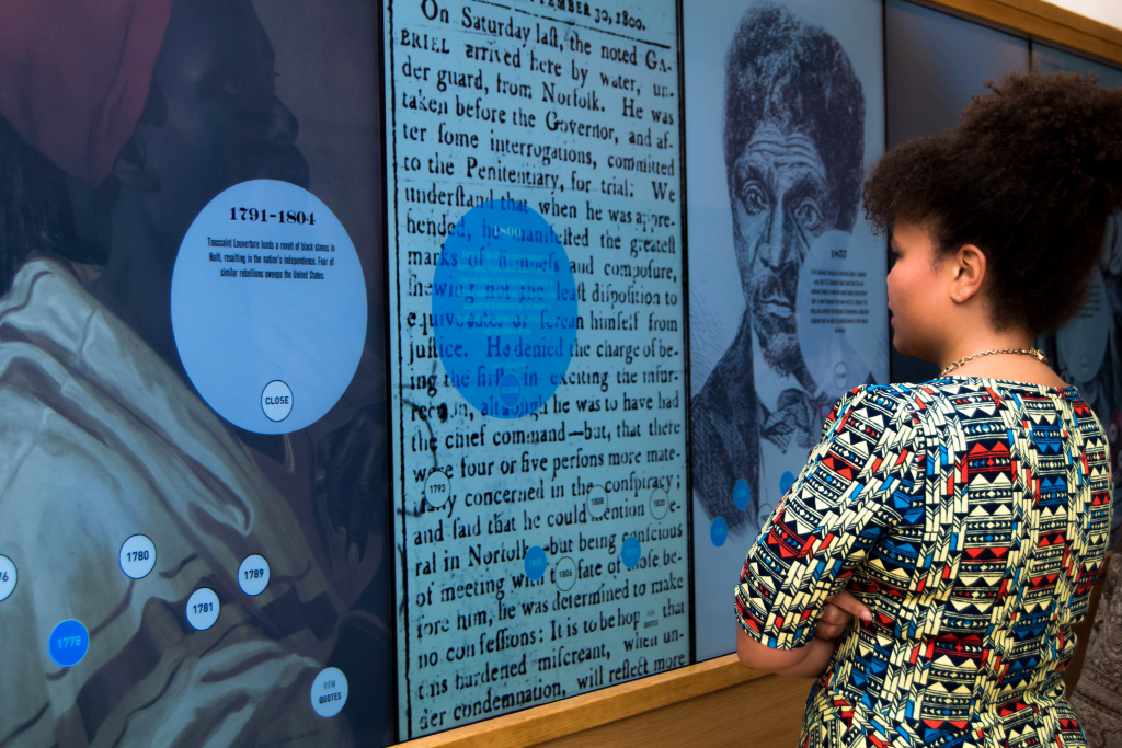 a young woman passes through an exhibit at a black history museum and cultural center
