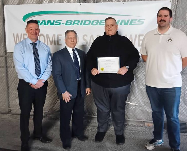 Motorcoach Driver Mark Obert is presented with a certificate of achievement and company pin for 26 years of safe driving. Pictured left to right are: Mark Ertel, Vice President of Operations; Tom JeBran, President; Mark Obert, Driver; and Shane Gray, Transportation Manager.