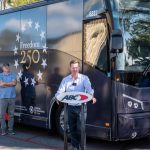 Fred Ferguson at a podium in front of a "Freedom 250" branded motorcoach addressing ABC employees